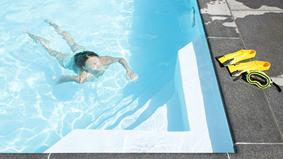 Flicka som simmar under vatten i en pool